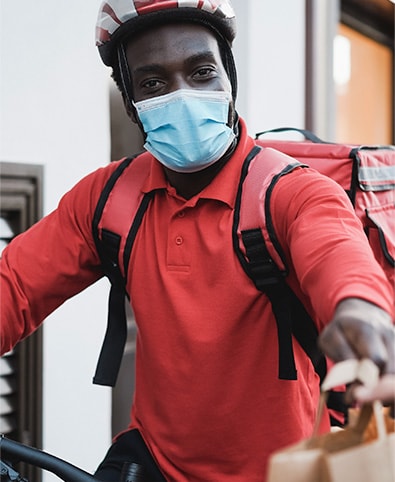 A BringMe-Food rider in a red uniform handing over a delivery bag