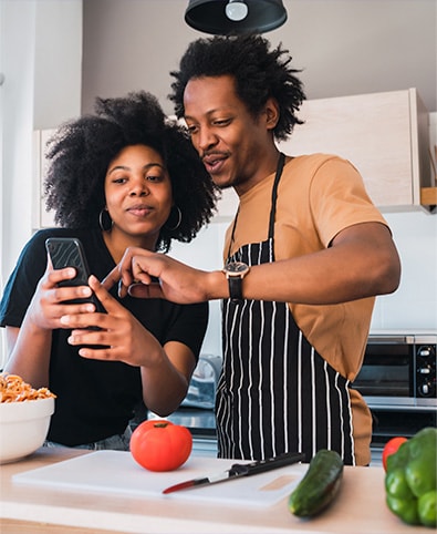 A couple in their kitchen browsing a phone together