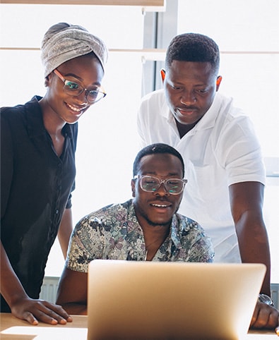 Three colleagues smiling at a laptop together